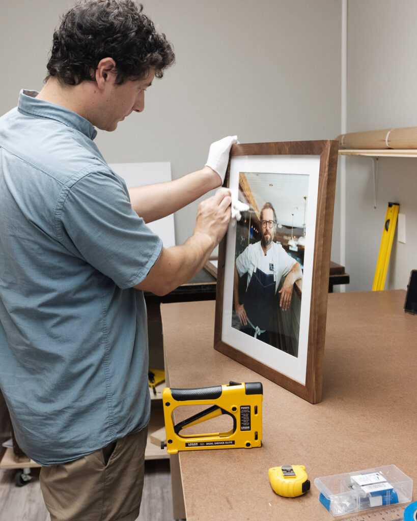 Andy DelGiudice of Cove Creative putting the finishing touches on a picture frame made out of salvaged wood.